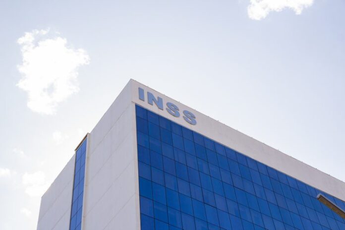 Prédio branco com letreiro azul escrito: INSS