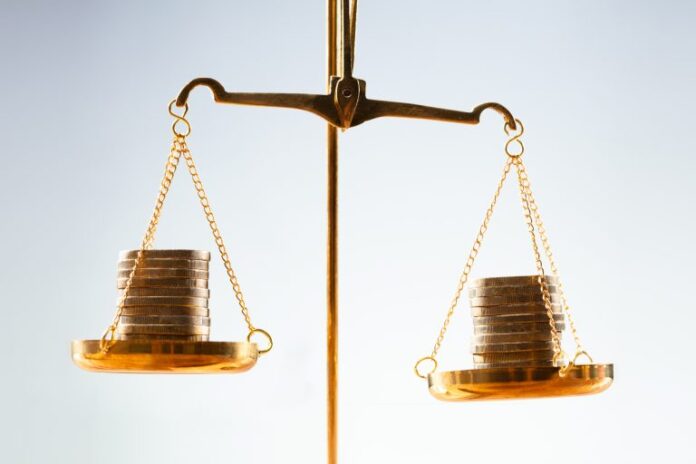 Balança de dois pratos com pilhas de moedas equilibrando os lados