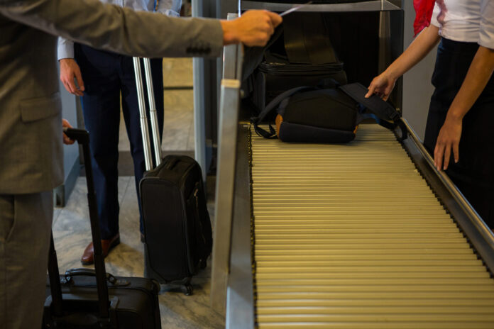 Female staff checking passengers luggage on conveyor belt in airport Fonte Freepik